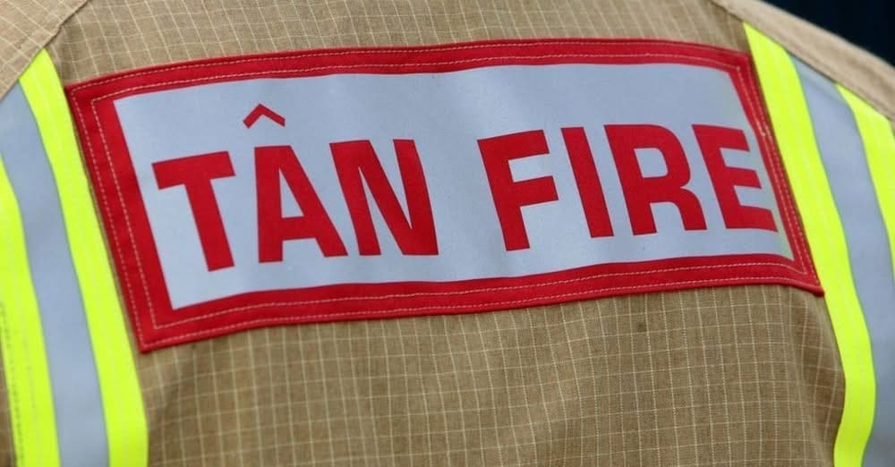 Tan Fire badge on the rear of a South Wales Fire and Rescue Service firefighter's tunic, Welsh language insignia worn by SWFRS personnel